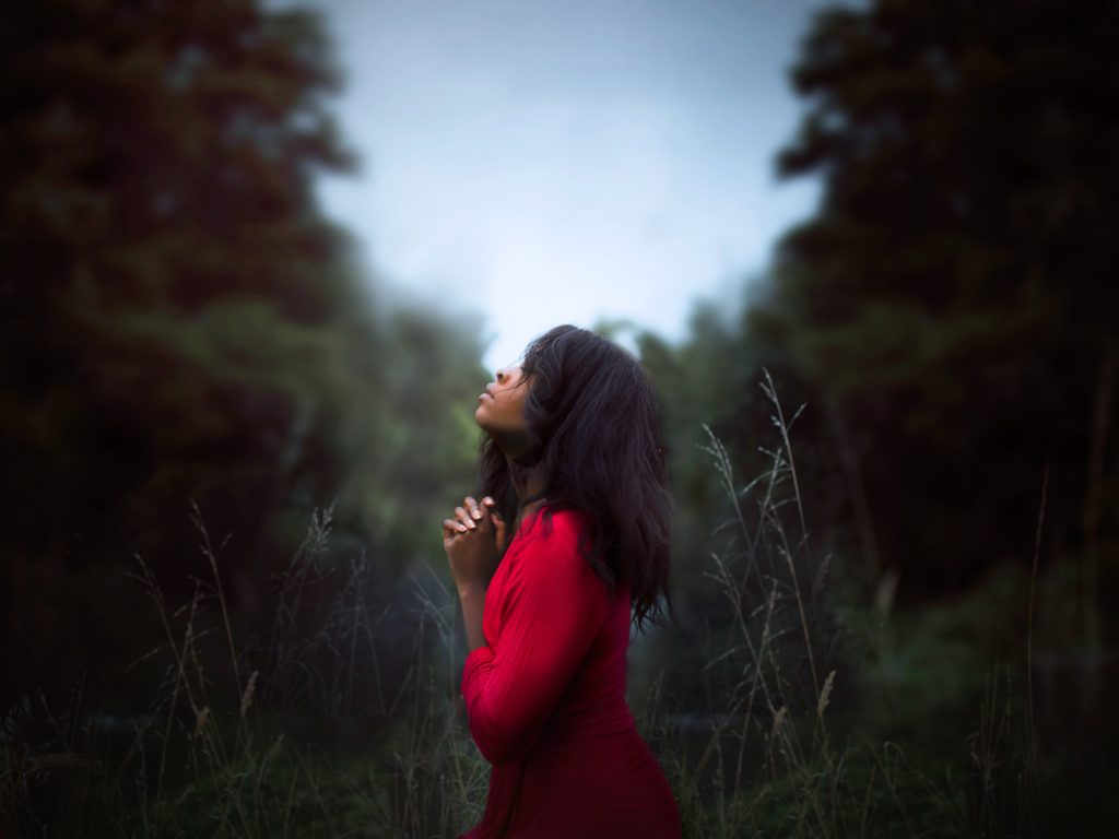 Woman in red shirt praying for guidance at a christian 12 step program