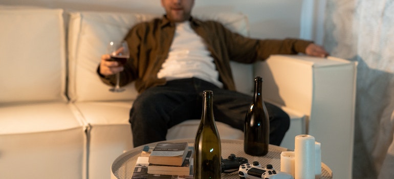 Man sitting on a couch, drinking.