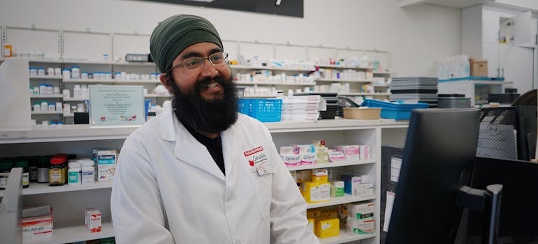 Pharmacist standing behind the counter and smiling.