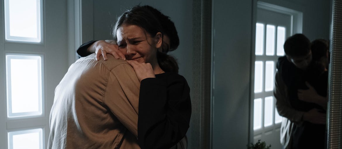 Woman crying and hugging her husband.